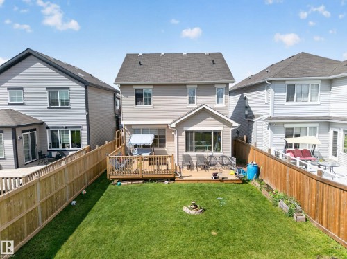 Expansive backyard featuring a manicured lawn, a wood deck, wood privacy fencing, and a built-in fire pit - 1927 51 Street Sw, Edmonton, AB - Outdoor With Deck Patio Veranda With Exterior