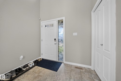 Entryway featuring a white paneled door with glass inserts, a full-length sidelight, and a built-in storage closet with bi-fold doors - 1927 51 Street Sw, Edmonton, AB - Indoor Photo Showing Other Room