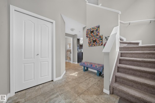Neutral tone wall paint, bi-fold closet doors, tile flooring, and carpeted staircase - 1927 51 Street Sw, Edmonton, AB - Indoor Photo Showing Other Room