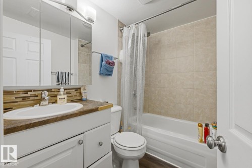 White vanity with wood-finish countertop, integrated sink, and modern faucet - 9712 162 St Nw, Edmonton, AB - Indoor Photo Showing Bathroom