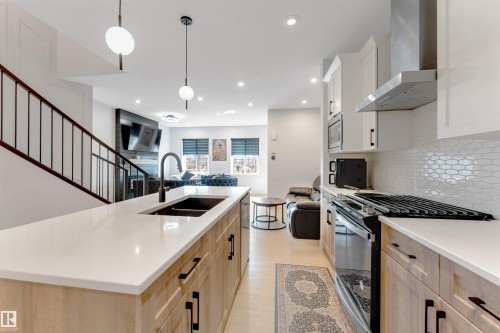 Kitchen island with an undermount sink, a gooseneck faucet, and pendant lighting - 1263 Watt Drive Sw, Edmonton, AB - Indoor Photo Showing Kitchen With Double Sink With Upgraded Kitchen