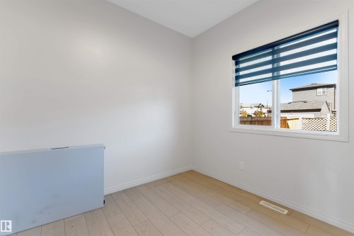Laminate flooring, white walls, and a large window with privacy blinds - 1263 Watt Drive Sw, Edmonton, AB - Indoor Photo Showing Other Room