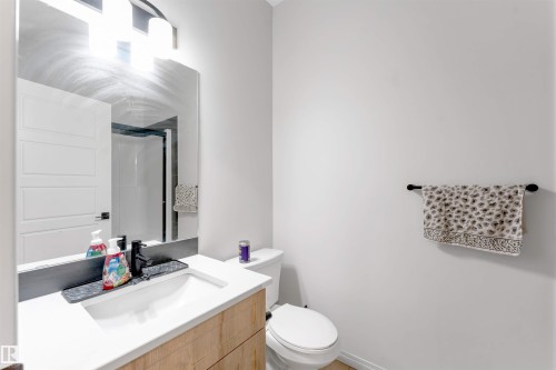 White vanity with wood-finish cabinetry, integrated sink, and black faucet - 1263 Watt Drive Sw, Edmonton, AB - Indoor Photo Showing Bathroom