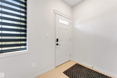White entry door with decorative glass inserts, matte black hardware, and polished tile flooring - 1263 Watt Drive Sw, Edmonton, AB - Indoor Photo Showing Other Room