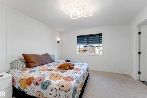 Wall paneling detail, wall-mounted sconce lighting, window with blinds, modern ceiling light fixture, and carpet flooring - 1263 Watt Drive Sw, Edmonton, AB - Indoor Photo Showing Bedroom