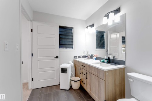 Dual vanity with integrated sinks, wood-finish cabinetry, and matte black hardware - 1263 Watt Drive Sw, Edmonton, AB - Indoor Photo Showing Bathroom