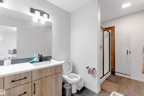 Bathroom featuring a light wood-finish vanity with black hardware, white countertop, rectangular sink with a matte black faucet, and a shower with a dark framed glass enclosure - 1263 Watt Drive Sw, Edmonton, AB - Indoor Photo Showing Bathroom