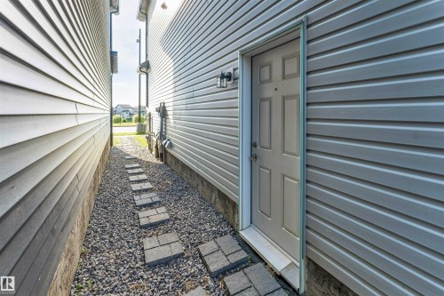 Side exterior entrance featuring panel siding and a stepping stone pathway - 1263 Watt Drive Sw, Edmonton, AB - Outdoor