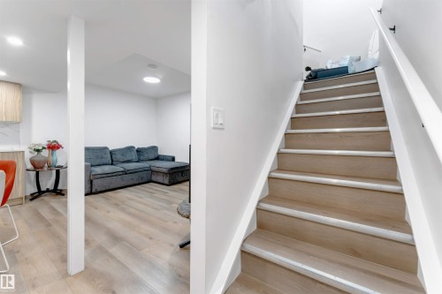 Wood-finish flooring throughout, white painted walls, recessed lighting, and a straight staircase with a white handrail - 1263 Watt Drive Sw, Edmonton, AB - Indoor Photo Showing Other Room