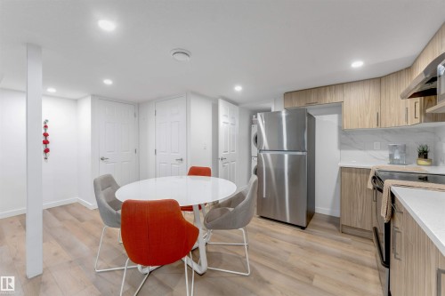Open concept kitchen with wood-finish flooring, light wood cabinetry, white stone countertops, and a white tile backsplash - 1263 Watt Drive Sw, Edmonton, AB - Indoor