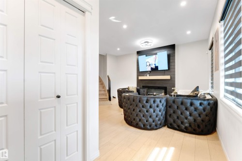 Recessed lighting, wood-finish flooring, fireplace with wood-paneled accent wall, built-in shelf, and ceiling fan - 1263 Watt Drive Sw, Edmonton, AB - Indoor With Fireplace