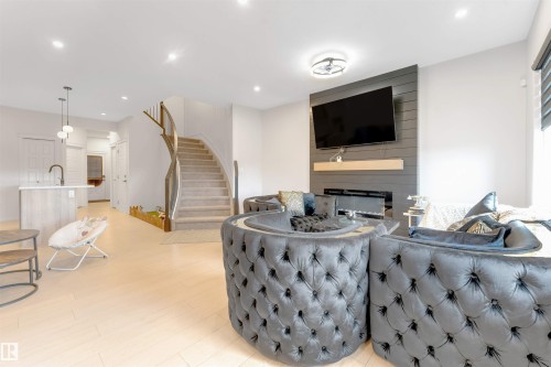 Recessed ceiling lighting, wood-finish flooring, built-in fireplace, curved staircase with wood railing, and a kitchen island with pendant lighting - 1263 Watt Drive Sw, Edmonton, AB - Indoor