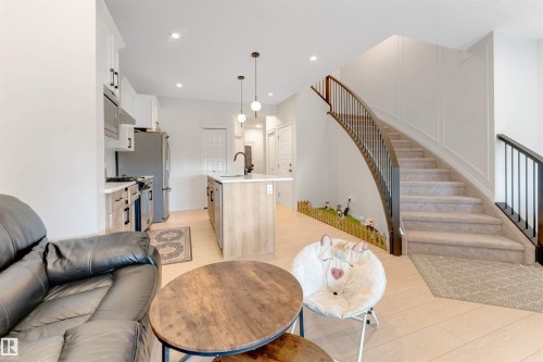 Modern kitchen with light wood-finish cabinetry, stainless steel appliances, and a central island with a sink and pendant lighting - 1263 Watt Drive Sw, Edmonton, AB - Indoor Photo Showing Living Room