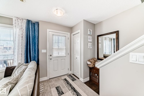 Entryway featuring a white paneled door with glass insert, wood-finish flooring, and a built-in closet with bifold doors - #138 655 Tamarack Rd Nw, Edmonton, AB - Indoor Photo Showing Other Room