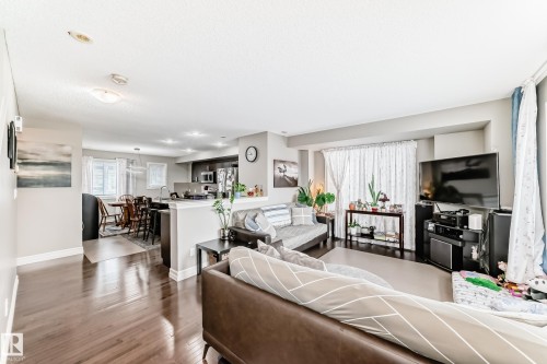 Hardwood-finish flooring throughout, recessed lighting, and a kitchen with dark cabinetry and stainless steel appliances - #138 655 Tamarack Rd Nw, Edmonton, AB - Indoor Photo Showing Living Room