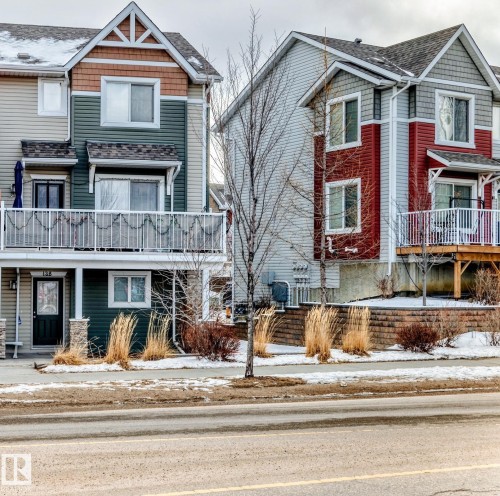 Multi-level townhome exterior featuring siding, upper balcony with railing, and a lower-level entry - #138 655 Tamarack Rd Nw, Edmonton, AB - Outdoor With Facade