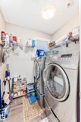 Laundry area featuring wood-finish flooring, overhead ceiling light, and a window with blinds - #138 655 Tamarack Rd Nw, Edmonton, AB - Indoor Photo Showing Laundry Room