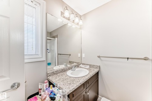 Vanity with integrated sink, speckled countertop, and dark wood-finish cabinetry - #138 655 Tamarack Rd Nw, Edmonton, AB - Indoor Photo Showing Bathroom