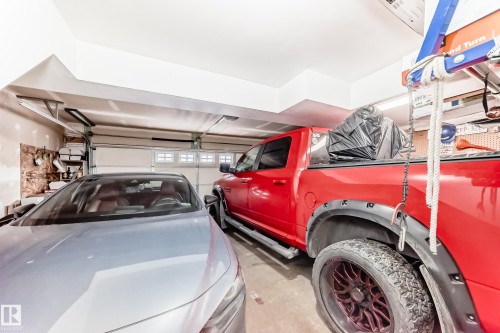 Attached two-car garage featuring a white overhead door with upper window inserts - #138 655 Tamarack Rd Nw, Edmonton, AB - Indoor Photo Showing Garage