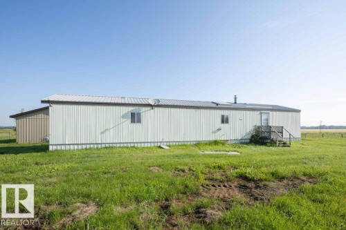 Corrugated metal siding with a light finish, pitched metal roof, and an exterior wooden staircase - 26417 Twp Rd 582, Rural Westlock County, AB - Outdoor