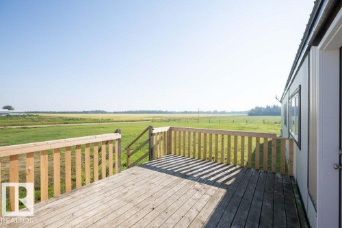 Expansive wood deck with natural wood railing, featuring a clear rural backdrop - 26417 Twp Rd 582, Rural Westlock County, AB - Outdoor With Deck Patio Veranda With View
