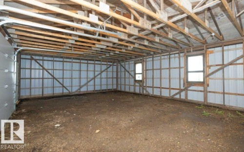 Exposed wood beam ceiling, corrugated metal wall panels, two windows, and overhead garage door track system - 26417 Twp Rd 582, Rural Westlock County, AB - Indoor Photo Showing Other Room