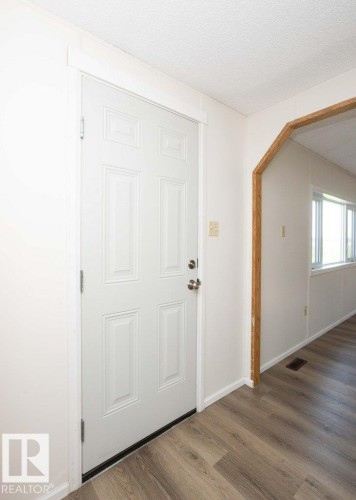 Panel-style entry door with satin nickel hardware, wood-finish flooring, and white trim - 26417 Twp Rd 582, Rural Westlock County, AB - Indoor Photo Showing Other Room