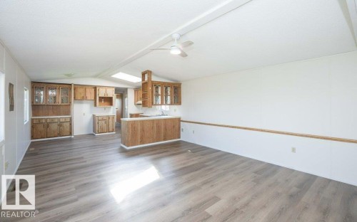 Open-concept common area featuring wood-finish flooring, a ceiling fan, and a kitchen with wood cabinetry - 26417 Twp Rd 582, Rural Westlock County, AB - Indoor