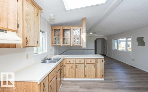 Kitchen with wood-finish cabinetry, white countertops, a double basin sink, and a skylight - 26417 Twp Rd 582, Rural Westlock County, AB - Indoor