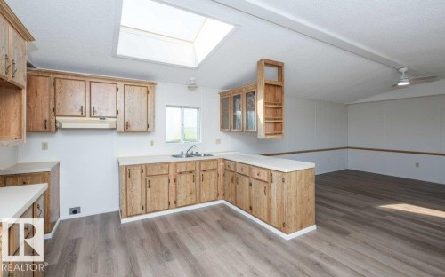 Kitchen featuring wood-finish cabinetry, white countertops, a stainless steel sink, and a prominent skylight - 26417 Twp Rd 582, Rural Westlock County, AB - Indoor Photo Showing Kitchen With Double Sink