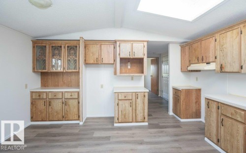 Kitchen featuring extensive wood-finish cabinetry, white countertops, wood-finish flooring, and a ceiling-mounted skylight - 26417 Twp Rd 582, Rural Westlock County, AB - Indoor Photo Showing Kitchen