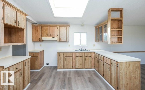 Kitchen featuring wood-finish cabinetry, light-toned countertops, a window over the sink, and a skylight - 26417 Twp Rd 582, Rural Westlock County, AB - Indoor Photo Showing Kitchen With Double Sink