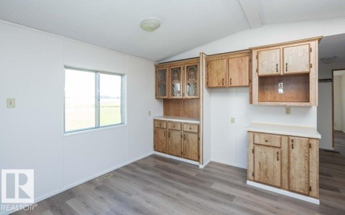 Wood-finish flooring, built-in cabinetry with glass-front uppers, light countertops, and a double-pane window - 26417 Twp Rd 582, Rural Westlock County, AB - Indoor Photo Showing Other Room