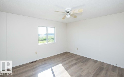 Wood-finish flooring, white walls, and a ceiling fan with light fixture - 26417 Twp Rd 582, Rural Westlock County, AB - Indoor Photo Showing Other Room