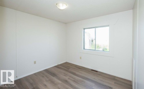 Wood-finish flooring, white walls, and a sliding window with white trim - 26417 Twp Rd 582, Rural Westlock County, AB - Indoor Photo Showing Other Room
