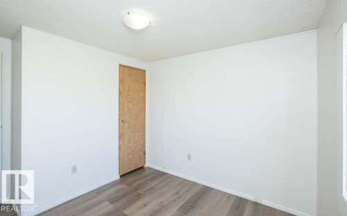 Wood-finish flooring, white walls, and a light-toned wood door with a brass-finish knob - 26417 Twp Rd 582, Rural Westlock County, AB - Indoor Photo Showing Other Room