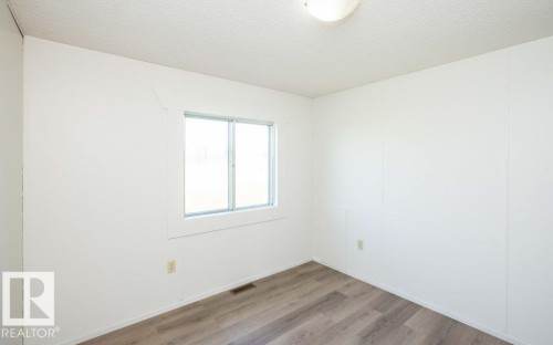 Wood-finish flooring, white paneled walls, and a single-pane sliding window - 26417 Twp Rd 582, Rural Westlock County, AB - Indoor Photo Showing Other Room