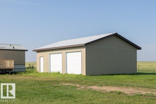 Detached garage structure featuring two overhead doors, a pedestrian entrance, and a sloped metal roof - 26417 Twp Rd 582, Rural Westlock County, AB - Outdoor