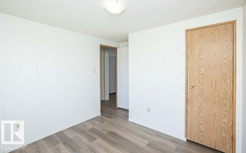 Wood-finish flooring with white wall panels and light wood-grain doors - 26417 Twp Rd 582, Rural Westlock County, AB - Indoor Photo Showing Other Room
