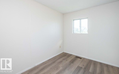 Wood-finish flooring, white walls, and a white-framed window - 26417 Twp Rd 582, Rural Westlock County, AB - Indoor Photo Showing Other Room