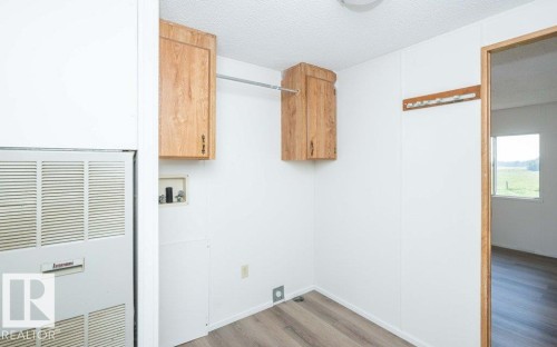 Utility room featuring wood-finish cabinetry, laminate countertop, and wood-frame doorway with transom window - 26417 Twp Rd 582, Rural Westlock County, AB - Indoor Photo Showing Other Room
