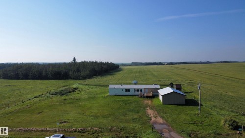 Expansive green fields surrounding the property, a light-colored residential structure with a deck, and an additional outbuilding - 26417 Twp Rd 582, Rural Westlock County, AB - Outdoor With View