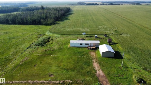 Expansive green acreage with a single-story residence, detached garage, and mature tree line - 26417 Twp Rd 582, Rural Westlock County, AB - Outdoor With View