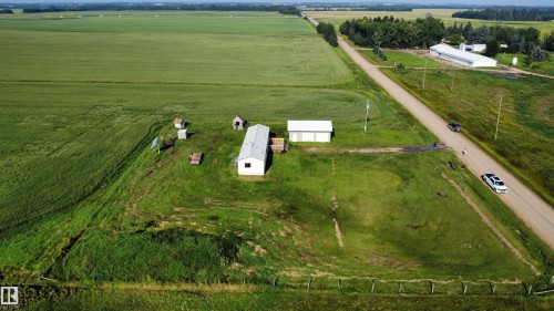 Aerial perspective showcasing rural land with agricultural fields, a single-story structure, and two additional small outbuildings - 26417 Twp Rd 582, Rural Westlock County, AB - Outdoor With View