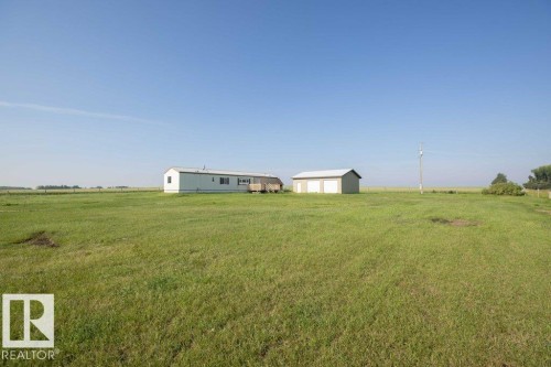 Expansive green landscape featuring a detached structure with multiple garage doors - 26417 Twp Rd 582, Rural Westlock County, AB - Outdoor