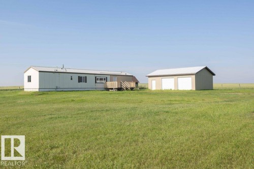 Expansive property featuring a single-story residence with a wood deck, a detached two-car garage, and a separate side entry door - 26417 Twp Rd 582, Rural Westlock County, AB - Outdoor