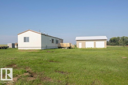 Manufactured home with white siding, a brown roof, and an exterior wood deck - 26417 Twp Rd 582, Rural Westlock County, AB - Outdoor