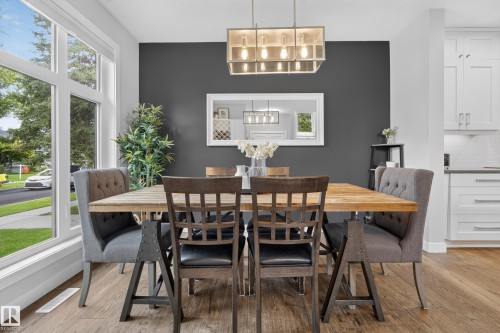 Expansive multi-pane window, wood-finish flooring, contemporary chandelier, white shaker cabinetry, and light-toned backsplash - 11018 122 Street Nw, Edmonton, AB - Indoor Photo Showing Dining Room