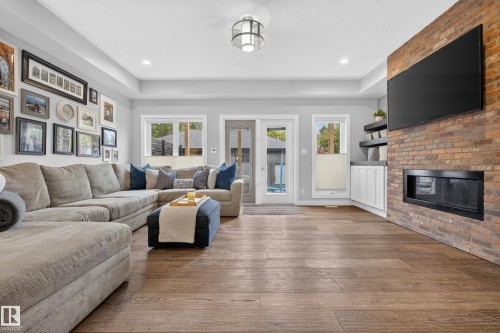 Expansive wood-finish flooring, recessed lighting, and a brick-finish fireplace - 11018 122 Street Nw, Edmonton, AB - Indoor Photo Showing Living Room With Fireplace