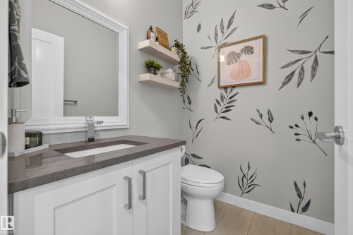 White vanity with brushed nickel hardware, integrated rectangular sink, gray countertop, and wood-finish flooring - 11018 122 Street Nw, Edmonton, AB - Indoor Photo Showing Bathroom